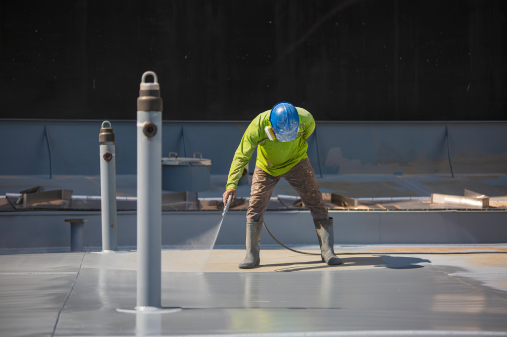 Roofing working applying a commercial roof coating to a business roof.
